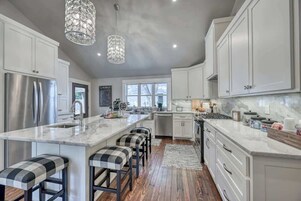Una cocina moderna con una isla grande, electrodomésticos de acero inoxidable y taburetes de bar.