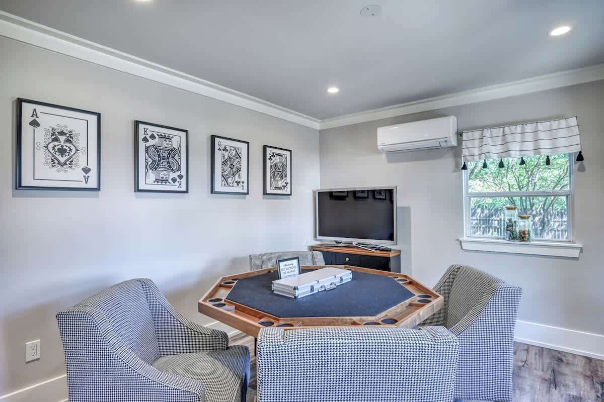 A room with a round table, two patterned chairs, a flat-screen TV, and framed artwork on the wall.