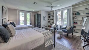 A bedroom with two beds, a bookshelf, a desk, and a chair.