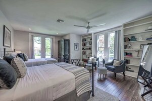 Un dormitorio con dos camas, una estantería, un escritorio y una silla.