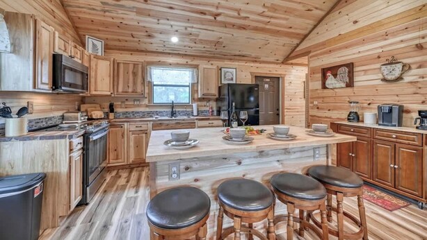 Une cuisine de style rustique, avec des éléments en bois, un îlot central, des tabourets de bar et un réfrigérateur.