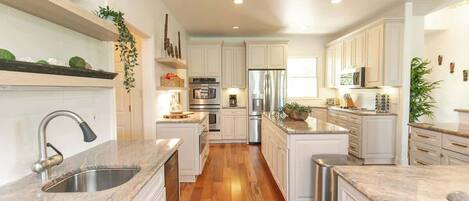 A modern kitchen with white cabinetry, stainless steel appliances, and a wooden floor.