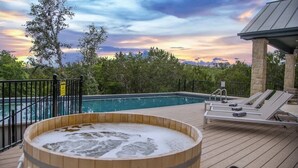 Une terrasse en bois avec un jacuzzi, une piscine et des chaises longues.