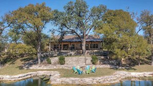 A house with a stone patio and a pond, surrounded by trees. - Ranch Retreat Combo With Stunning Creek View-fire Pit (Fredericksburg)