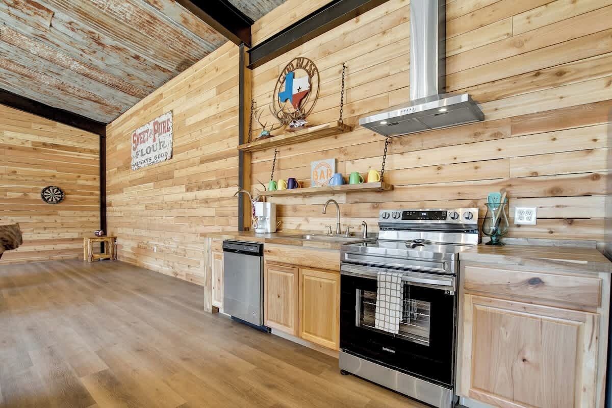 A kitchen with wooden walls, a dishwasher, an oven, and a coffee machine.