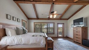 A bedroom with a wooden bed, a ceiling fan, a TV, and a dresser. - Ranch Retreat Combo With Stunning Creek View-fire Pit (Fredericksburg)