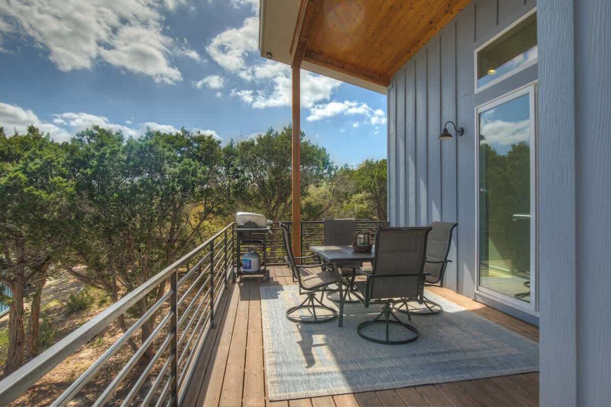Ein Balkon mit Tisch, Stühlen, einem Grill und Blick auf Bäume.
