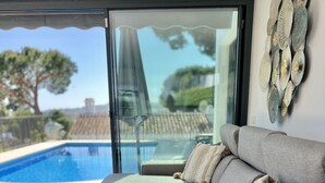 A modern living room with a gray sofa, two side tables, and a view of a swimming pool. - 22 - Villa in Cala de Mijas (La Cala de Mijas)