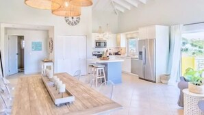 Una cocina amplia con una isla central, muebles blancos y electrodomésticos de acero inoxidable.