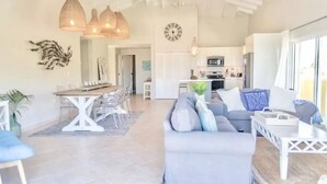 Amplia sala de estar con una mesa de comedor, un sofá y una cocina al fondo.