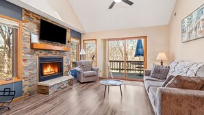 Una sala de estar con chimenea, un sofá, una mesa de centro y un balcón con una sombrilla azul.