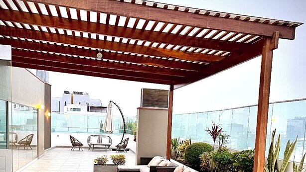 A rooftop terrace with wicker furniture, a pergola, and a view of the cityscape. - Unique Apartment. 5 Guests. 3 Bedrooms. 2 Baths. (Lima)