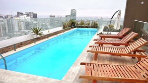 A rooftop pool with wooden loungers and a city view. - Unique Apartment. 5 Guests. 3 Bedrooms. 2 Baths. (Lima)