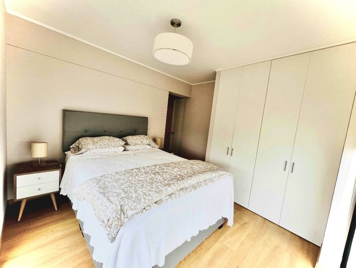 A bedroom with a bed, nightstand, wardrobe, and a ceiling light.