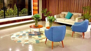 A modern living room with a sofa, two blue armchairs, a coffee table, and a large window with plants. - Unique Apartment. 5 Guests. 3 Bedrooms. 2 Baths. (Lima)