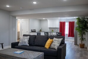 Ein modernes Wohnzimmer mit einem dunklen Sofa, einem Couchtisch und einer Zimmerpflanze.