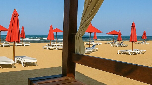 A beachside lounge with a wooden bench, red umbrellas, and white lounge chairs. - The Perfect Beach Escape in Porto Said (Al-Manasrah)