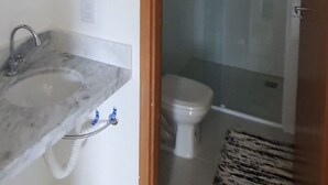A bathroom with a shower, toilet, and a sink with a mirror.