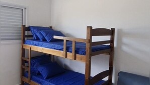 A bunk bed with blue bedding in a room with white walls and a ceiling fan.