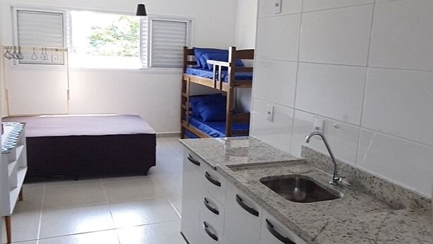 A compact kitchen with white cabinets, a granite countertop, and a built-in sink. There is a small rug on the floor, and a ceiling fan is visible.