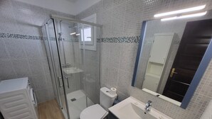 A modern bathroom with a glass-enclosed shower, a toilet, a sink, and a mirror. - San Marino Studio 7 (Los Cristianos)