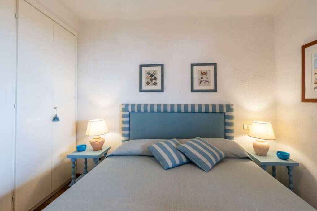 Ein Schlafzimmer mit einem Bett, zwei Nachttischen mit Lampen und zwei gerahmten Bildern an der Wand.
