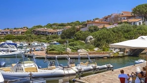A marina with several boats docked, surrounded by residential buildings and greenery. - Porto Rotondo Vista Incantevole sul Mare e Yacht (Olbia)
