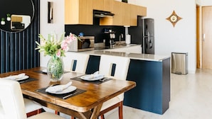 Cozinha moderna com armários de madeira, uma ilha central e um espaço de refeições com mesa posta para quatro pessoas.