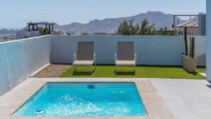 Piscina no terraço com duas espreguiçadeiras, mesa de bilhar pequena e vista para montanhas.