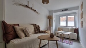 Un salón con sofá, una mesa redonda de madera y una ventana con vistas.