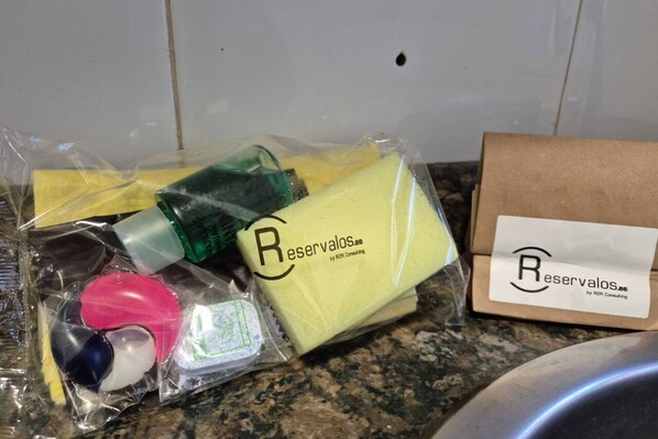 Una encimera de cocina con diversos productos envasados, incluyendo una esponja amarilla, una botella verde y un recipiente rosa.