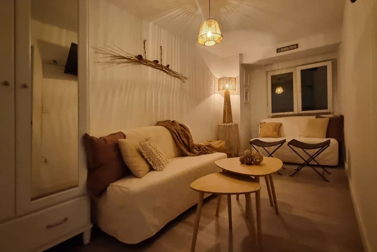 Una sala de estar acogedora con un sofá, una mesita redonda y una lámpara.