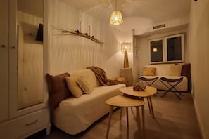 Una sala de estar acogedora con un sofá, una mesita redonda y una lámpara.
