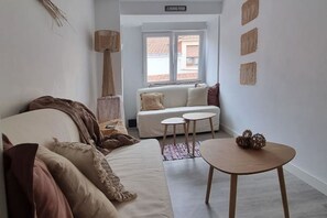 Una sala moderna con un sofá, dos mesitas redondas y una lámpara.