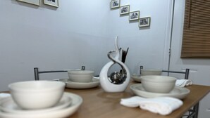 A dining table with white ceramic dishes and a silver utensil holder. - House of Treasure, a stylish property located 8 minute from Downtown Dallas. (Dallas)