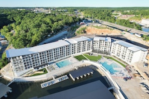 Un hotel moderno con piscina, rodeado de vegetación y un río.