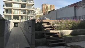 A multi-story residential building with balconies, a concrete pathway, and a staircase leading to a rooftop garden. - PB by medrano SUITS (Buenos Aires)