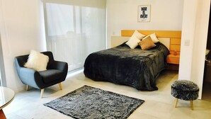 A modern bedroom with a bed, a chair, a rug, and a wall-mounted light fixture. - PB by medrano SUITS (Buenos Aires)