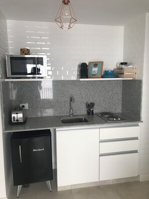 A compact kitchen with a microwave, toaster, sink, and dishwasher. - PB by medrano SUITS (Buenos Aires)