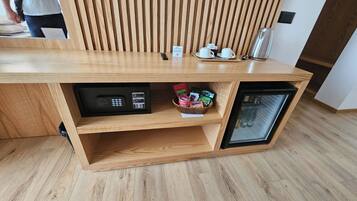 Una encimera de madera con una máquina de café, un refrigerador pequeño y una cesta de aperitivos.