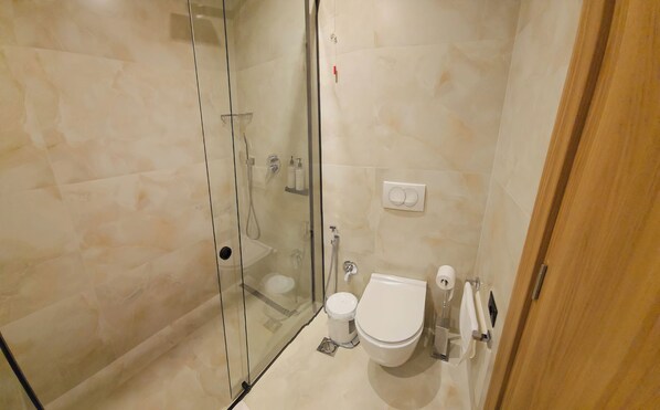 Un baño con ducha de mampara de vidrio, un inodoro y un lavamanos.