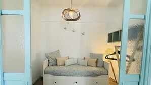 Une chambre avec un lit intégré, un luminaire suspendu et un parquet en bois disposé en motif chevrons.