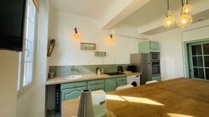 Une cuisine moderne avec une table en bois, un évier, un lave-linge et un réfrigérateur.