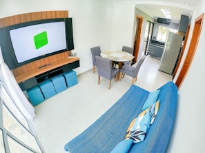 Uma sala de estar moderna com televisão, sala de jantar e cozinha.