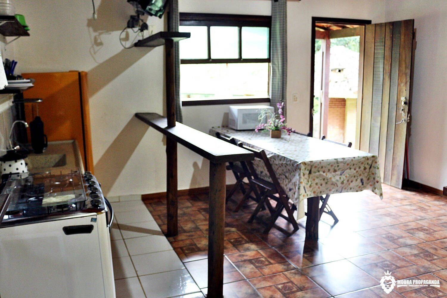 Een keuken met een fornuis, een magnetron en een tafel met stoelen.