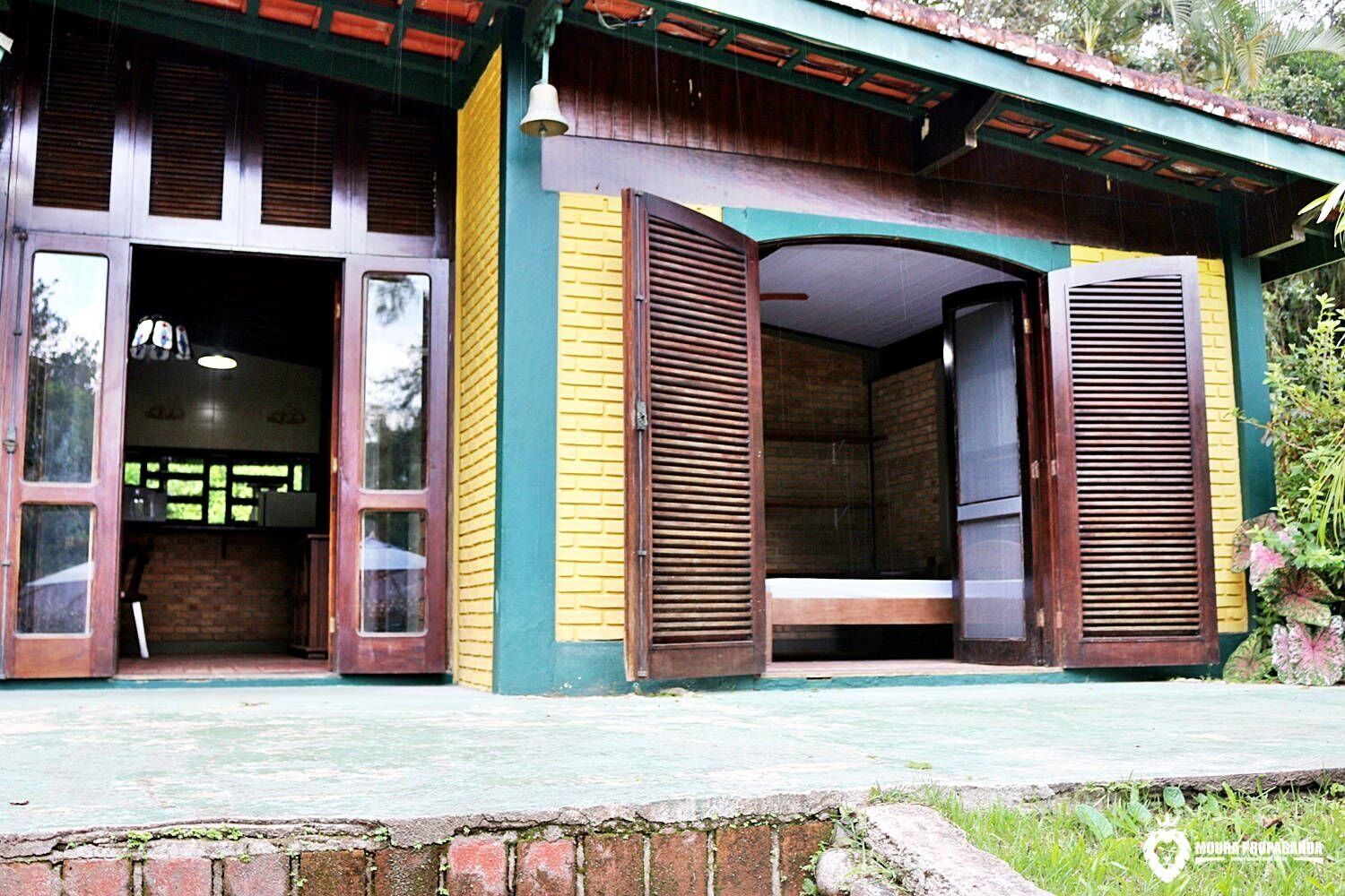 Un edificio con contraventanas de madera abiertas, un muro de ladrillo y un techo verde.