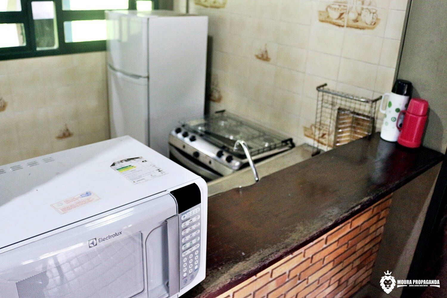 A kitchen with a white microwave, a gas stove, and a refrigerator.