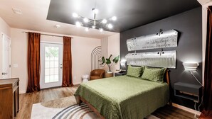 A modern bedroom with a large bed, a ceiling light fixture, a wall-mounted light, and a decorative metal piece.