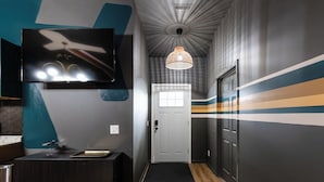 A hallway with a modern design, a flat-screen TV mounted on the wall, a small sink, and a decorative ceiling light.