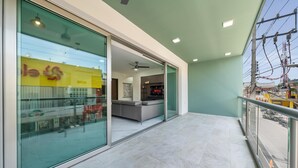 Een modern hotelinterieur met een glazen deur naar een balkon, een bank en een plafondventilator.